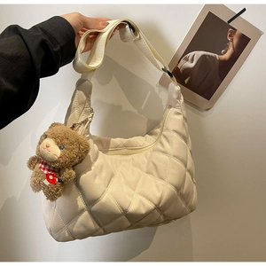 Detailed close-up of cream quilted nylon tote with adjustable strap and bear charm