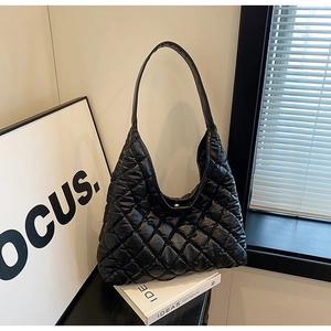 Detail of black quilted shoulder bag with glossy finish and minimalist crescent silhouette