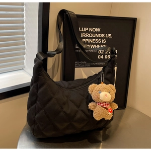 Detail of black quilted nylon hobo tote featuring a cute brown plush bear accessory