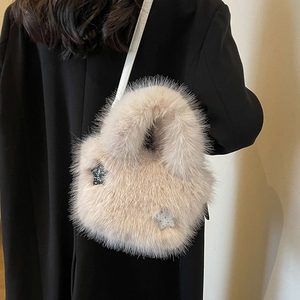 Plush faux fur bucket bag in soft pink with star charms and a slim leather strap