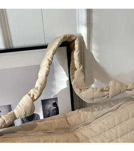 Détail du sac fourre-tout matelassé beige avec poignée renforcée et fermeture éclair en métal
