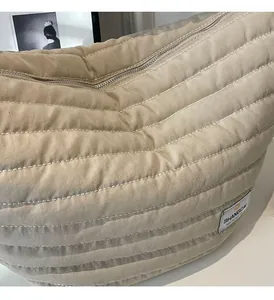 Détail du sac bandoulière matelassé en nylon beige avec fermeture éclair et étiquette