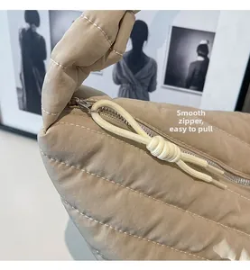 Détail de la fermeture éclair argentée et tirette nouée sur sac beige matelassé