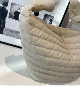 Détail d'un sac cabas en nylon matelassé beige avec large poignée et fermeture éclair en métal