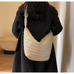Détail d'un sac bandoulière matelassé beige en nylon avec nœud de sangle et zip