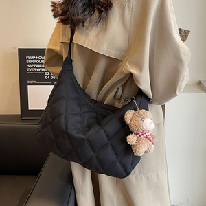 Quilted black nylon tote bag with teddy bear pendant shown on model in khaki coat