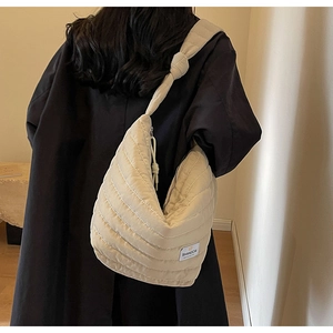 Détail du sac hobo en nylon matelassé beige avec large bandoulière et logo