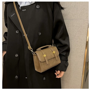 Close-up of brown vintage square bag featuring star embossing and gold metal buckles