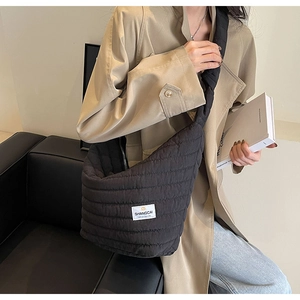Détail d'un sac à bandoulière en nylon matelassé noir avec étiquette de marque