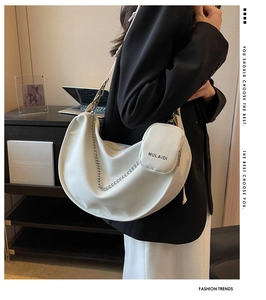 Sac demi-lune blanc avec chaîne argentée et pochette, porté dans un cadre moderne