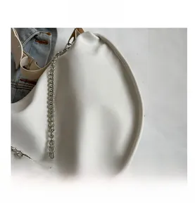 Détail de la texture du tissu en toile blanche et de la chaîne argentée du sac croissant