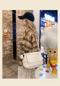 Detail of white canvas crossbody bag with flap cover and wide strap on model
