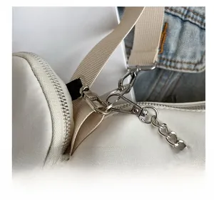 Détail des crochets argentés et de la chaîne sur un sac bandoulière en toile blanche