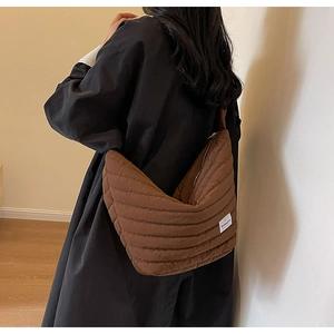 Vue latérale du sac bandoulière matelassé marron avec fermeture éclair et étiquette