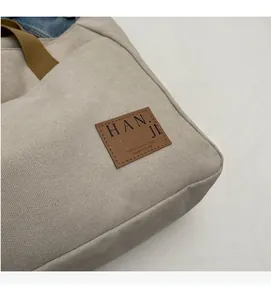 Close-up of canvas tote bag featuring a leather patch and durable woven handle detail