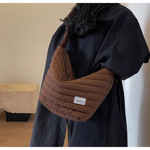 Détail d'un sac demi-lune matelassé marron foncé avec texture rembourrée et étiquette