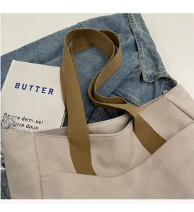 Detail of sturdy brown woven handles and stitching on a beige canvas tote bag