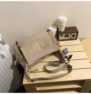 Detail of khaki nylon tote bag with XBOKA lettering and checkerboard pendant charm