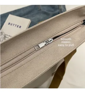 Detailed close-up of a smooth silver metal zipper on an off-white canvas tote bag