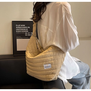 Détail du sac demi-lune beige en nylon matelassé avec étiquette tissée et zip à cordon
