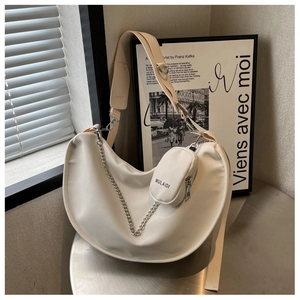 Détail du sac croissant blanc avec chaîne argentée et petite pochette ronde zippée