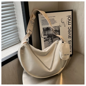 Détail du sac hobo blanc cassé avec chaîne argentée et mini porte-monnaie sur table