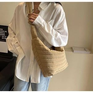 Détail du sac croissant en nylon matelassé beige avec coutures horizontales et bandoulière nouée