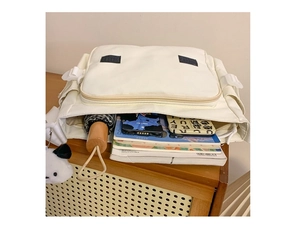 Detalle de un bolso tote de lona beige con espacio para libros y un colgante de panda