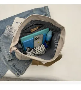 Detail view of spacious off-white canvas tote bag interior with striped lining and zipper pocket