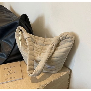 Détail d'un sac à main matelassé en nylon beige avec étiquette sur pierre