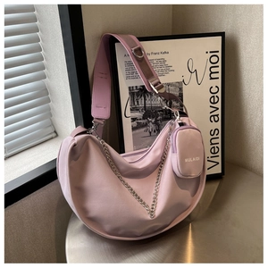 Détail du sac croissant lavande avec chaîne argentée et mini pochette sur table en métal
