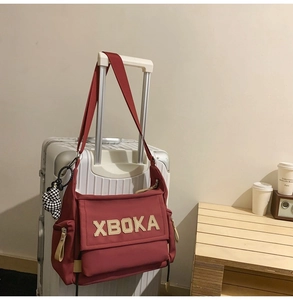 Detail of burgundy canvas tote bag with adjustable strap and plaid bear charm