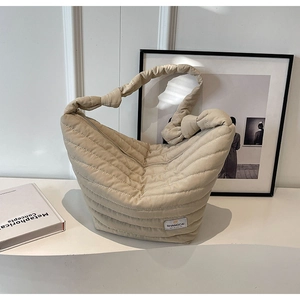 Détail d'un sac à main matelassé blanc cassé avec poignée froncée et étiquette de marque