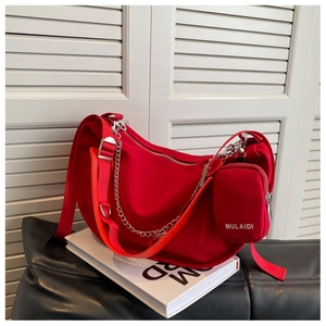 Détail d'un sac hobo rouge avec chaîne en métal et petite pochette assortie incluse