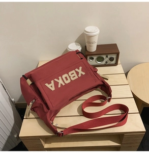 Close-up of a burgundy canvas tote bag with XBOKA leather patch on a wooden desk