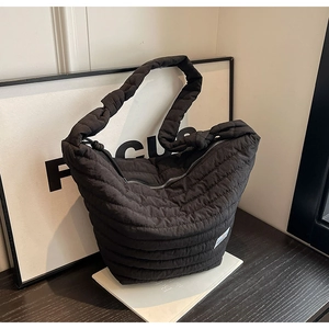 Détail du sac matelassé en nylon noir mettant l'accent sur la texture et la fermeture