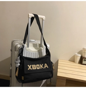 Detail of black canvas tote bag on luggage handle with checkerboard plush charm