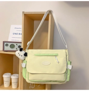 Detalle del bolso mensajero de lona con correa ajustable y colgante de cachorro suave