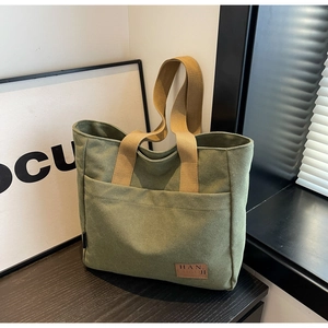 Close-up of olive green canvas tote bag with khaki straps and leather logo detail