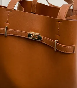 Close-up of brown leather handbag featuring gold turn-lock hardware and fine stitching
