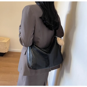 Detailed view of black PU leather hobo bag featuring retro texture and plush charm