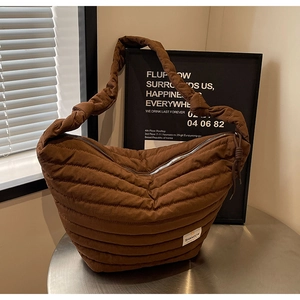 Vue détaillée du sac bandoulière en nylon matelassé marron avec bandoulière à nœud et logo