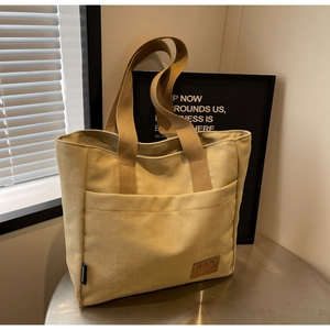 Detailed macro view of large canvas tote bag with leather logo tag on metal table