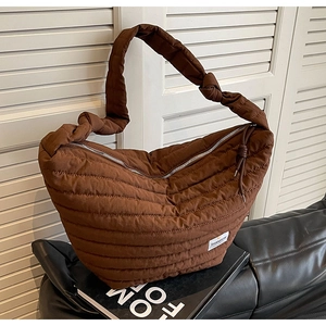 Détail d'un sac bandoulière en nylon matelassé marron avec bandoulière nouée et zip