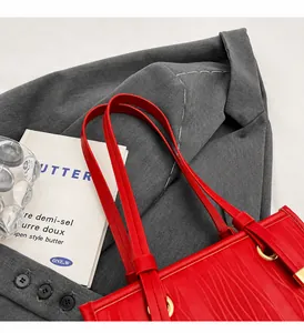 Draufsicht auf eine rote geprägte Handtasche aus Leder mit goldenen Metallbeschlägen