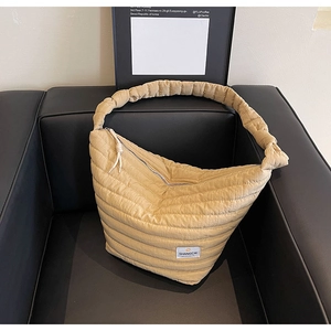 Détail du sac dumpling en nylon beige matelassé avec bandoulière froissée chic