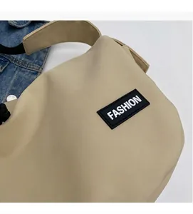 Detail of khaki nylon crossbody bag with fashion label next to a blue denim jacket