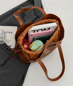 Top view of brown leather bucket bag showing large capacity with tablet and books