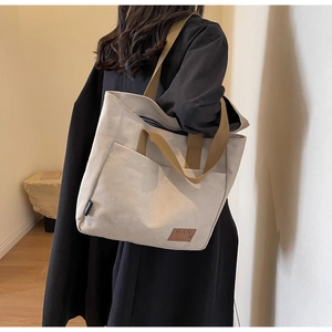 Detail of minimalist canvas tote bag with brown straps and dual handle design
