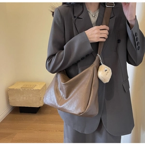 Detail of taupe crescent bag in pebbled PU leather with a cute plush doll charm